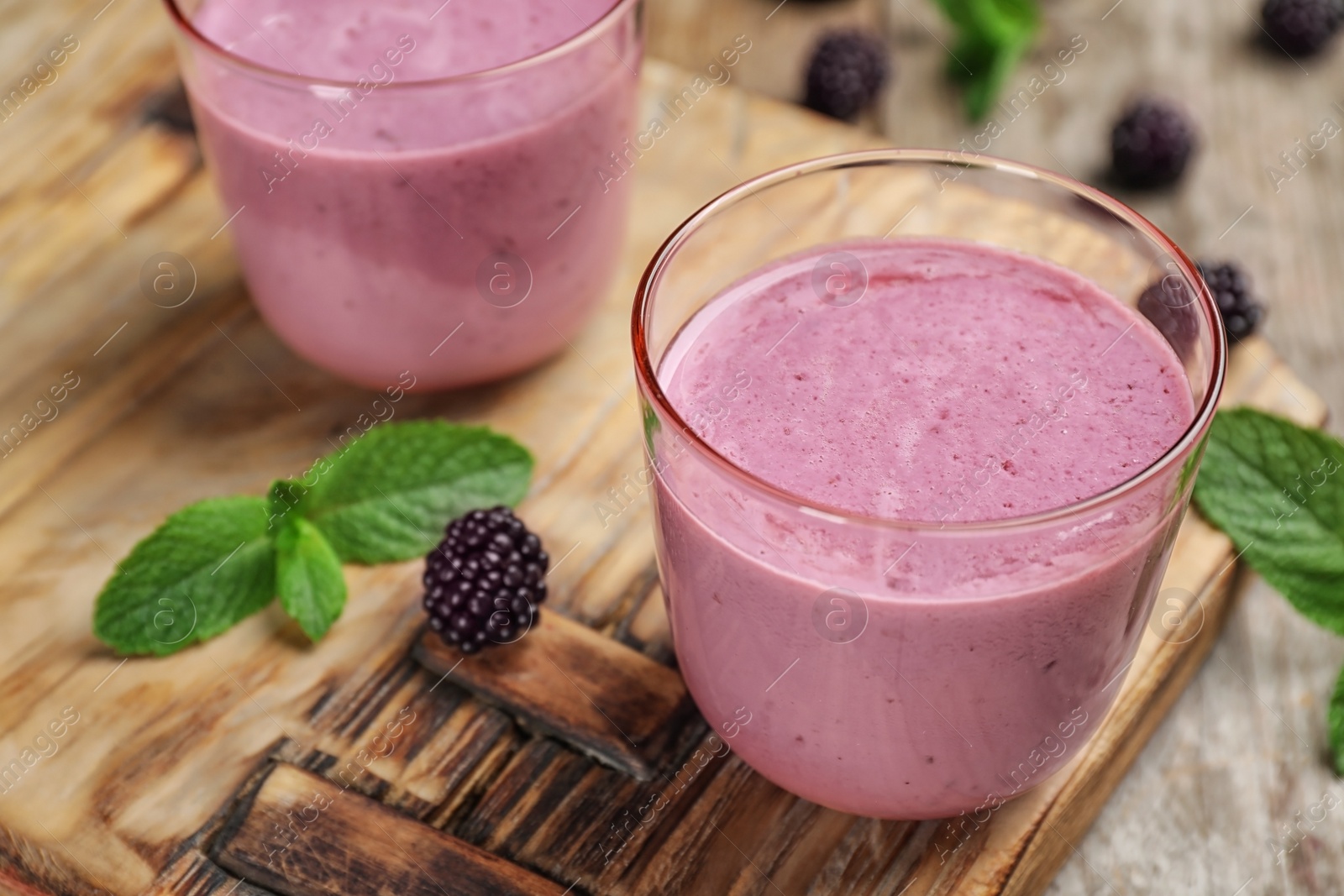 Photo of Glasses with blackberry yogurt smoothies on wooden board