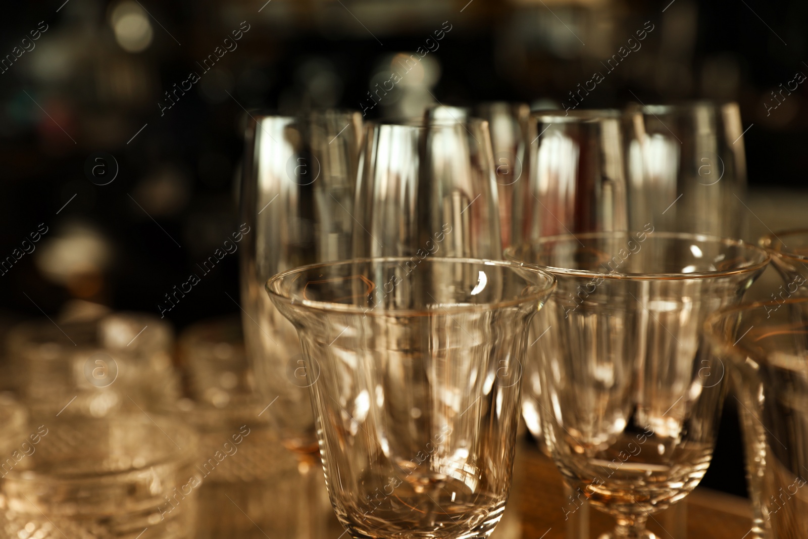 Photo of Different empty clean glasses in bar, closeup