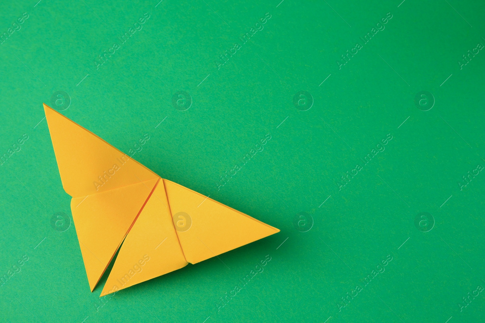 Photo of Origami art. Paper butterfly on green background, top view. Space for text
