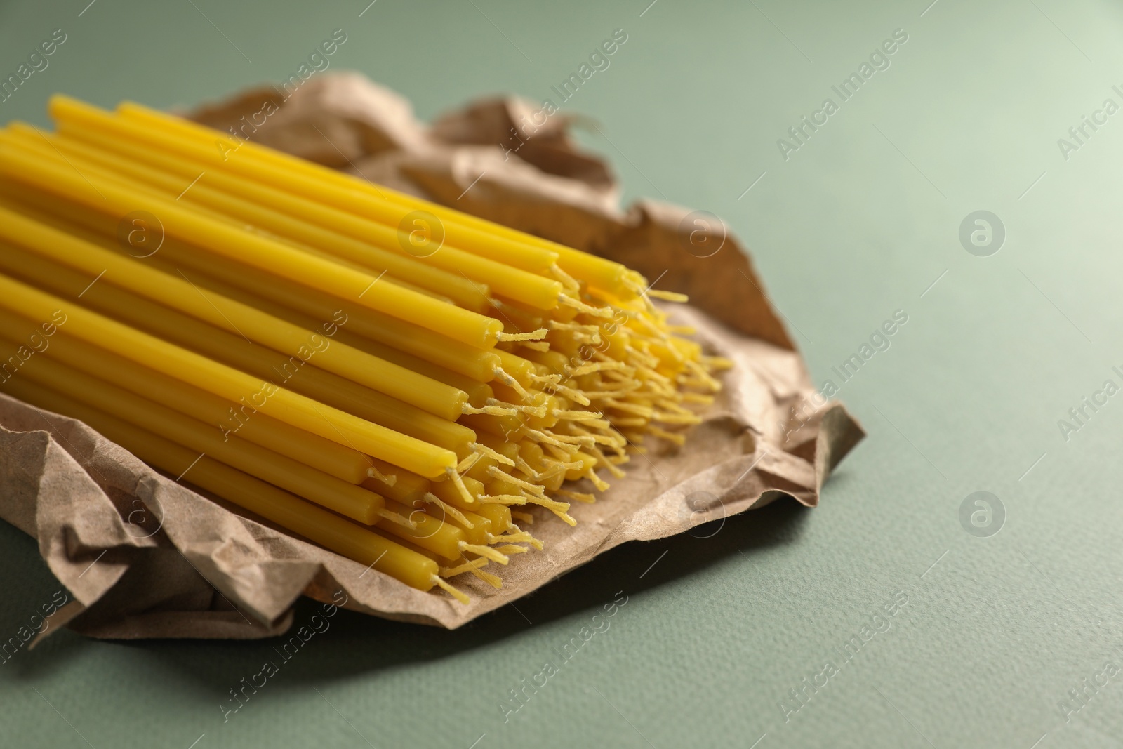 Photo of Many church wax candles on olive background, closeup. Space for text