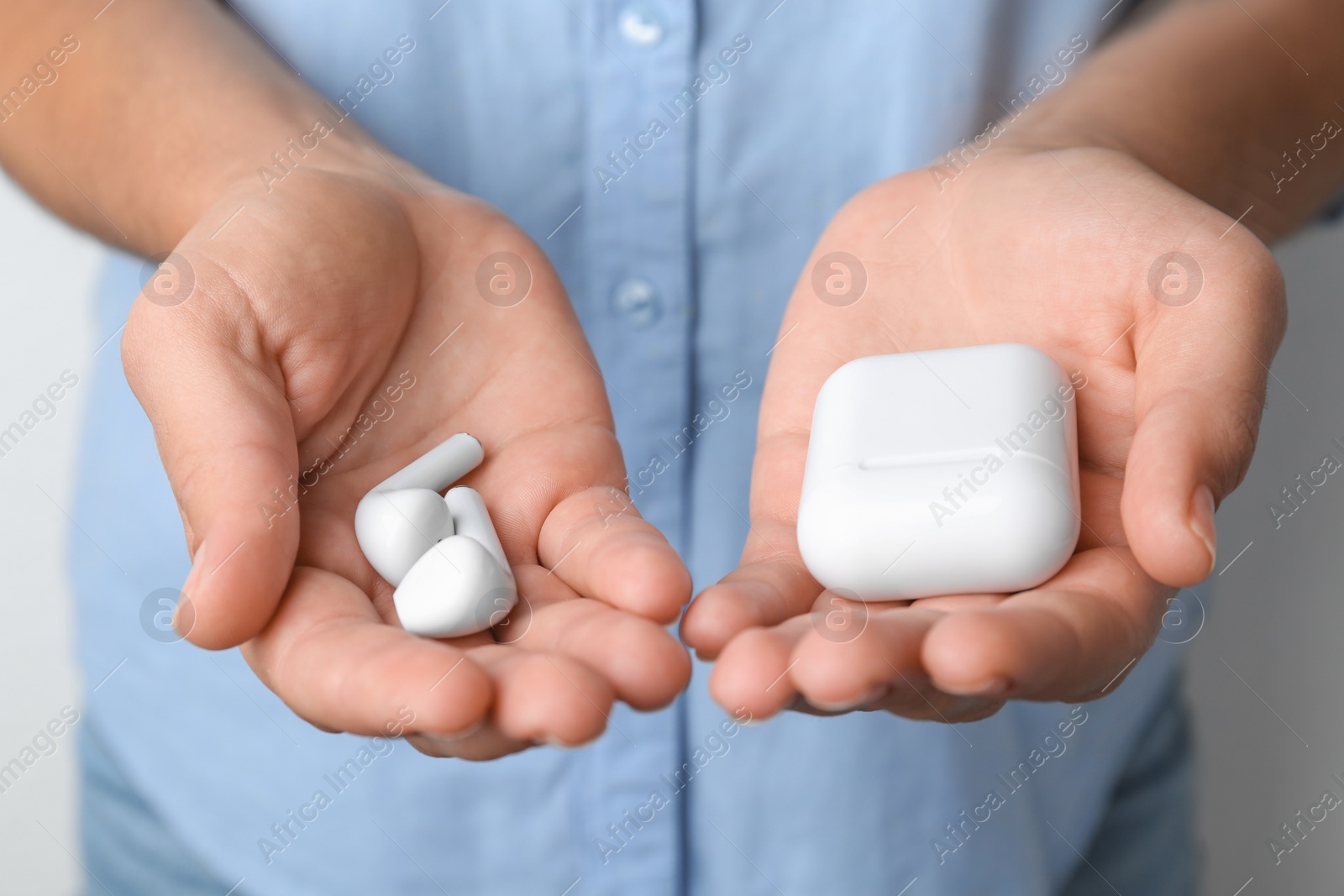 Photo of Woman holding wireless earphones and charging case, closeup