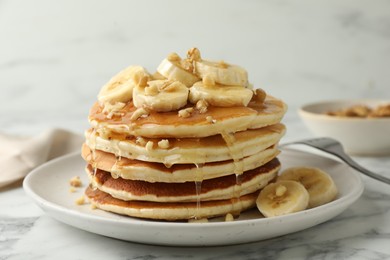 Photo of Delicious pancakes with bananas, walnuts and honey on white marble table, closeup