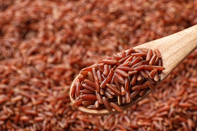 Wooden spoon with raw brown rice over cereal, closeup