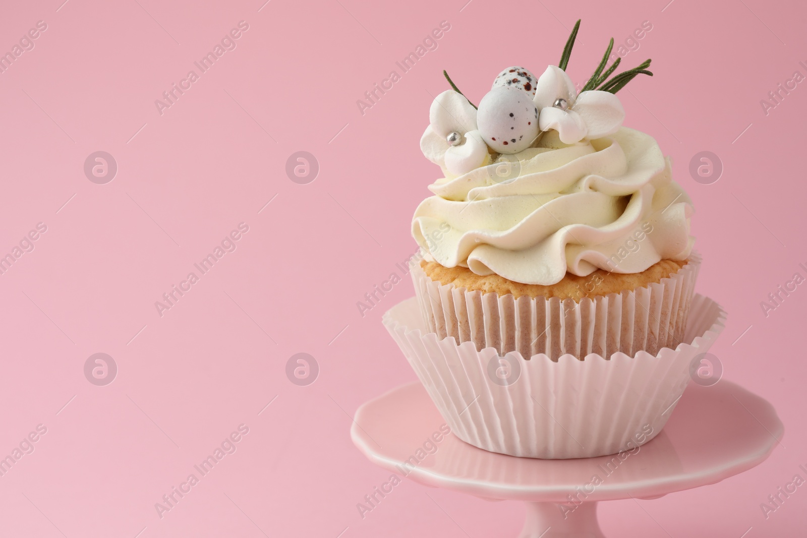 Photo of Tasty Easter cupcake with vanilla cream on pink background, space for text