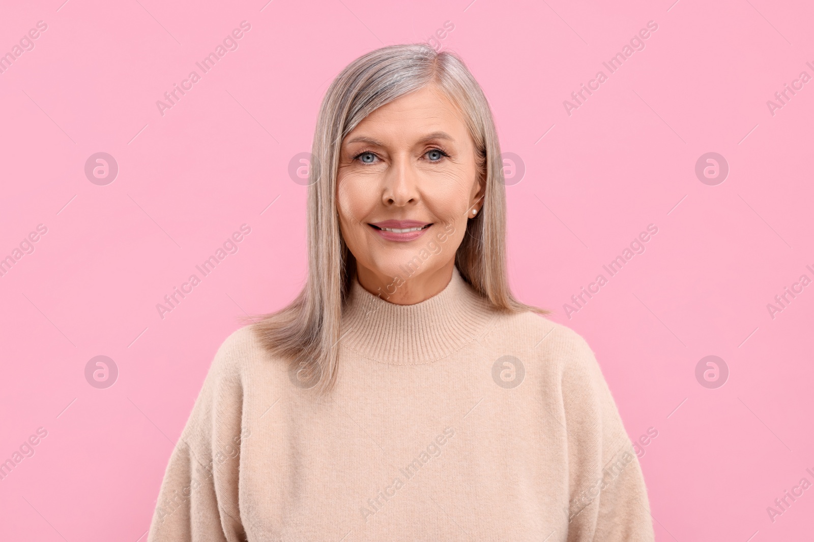 Photo of Portrait of beautiful middle aged woman on pink background