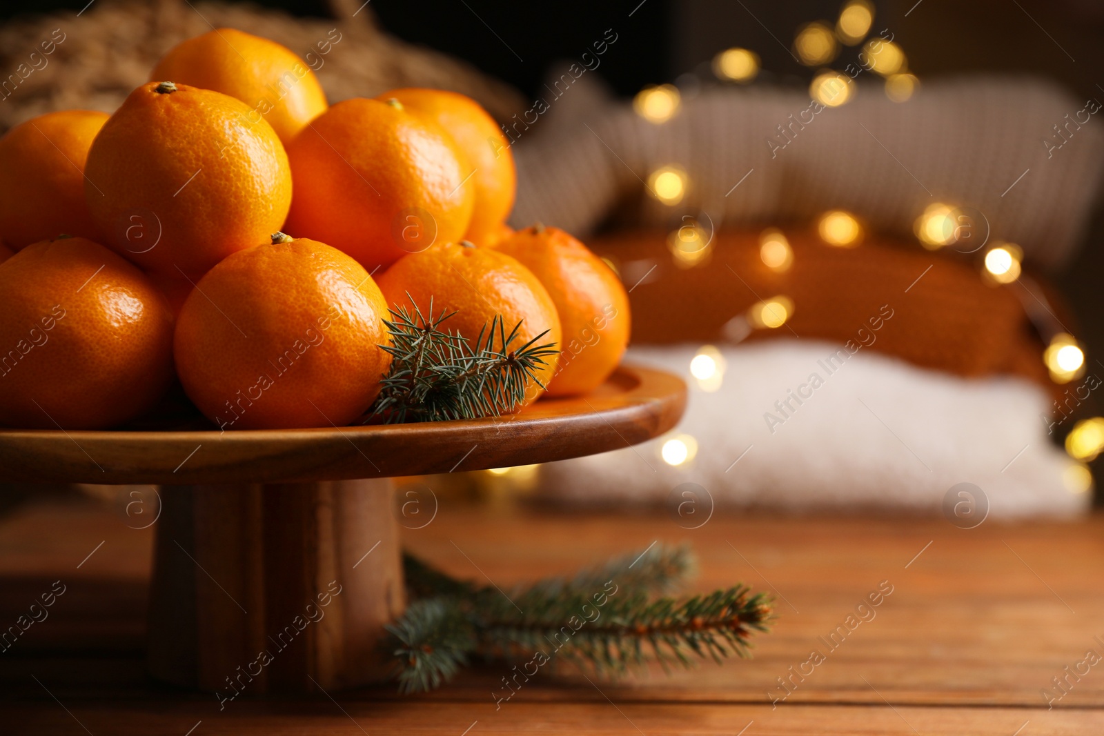 Photo of Stand with delicious ripe tangerines and fir twigs on wooden table. Space for text