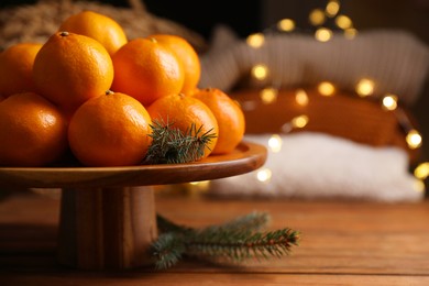 Stand with delicious ripe tangerines and fir twigs on wooden table. Space for text