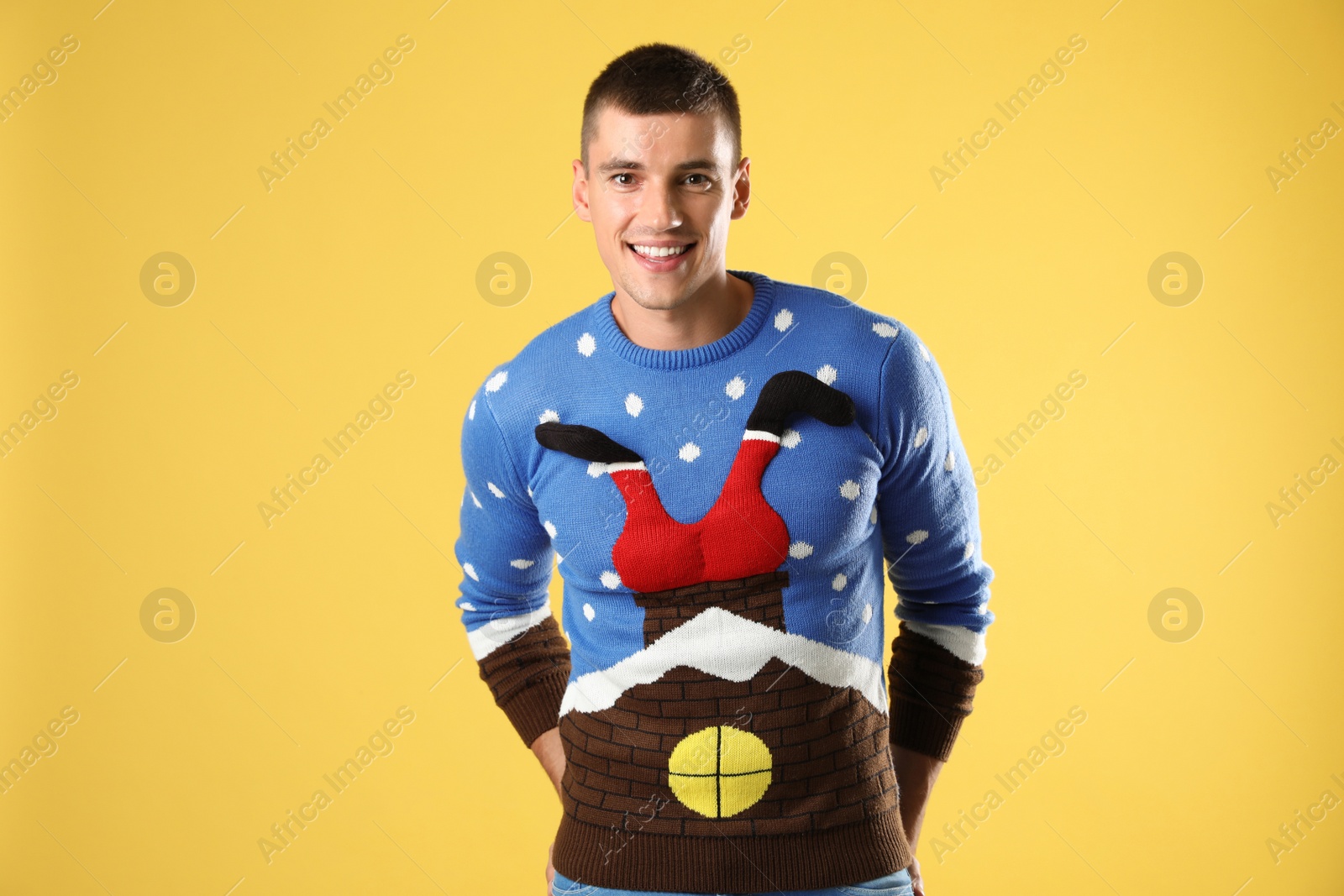 Photo of Portrait of happy young man in Christmas sweater on yellow background