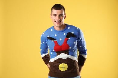Photo of Portrait of happy young man in Christmas sweater on yellow background