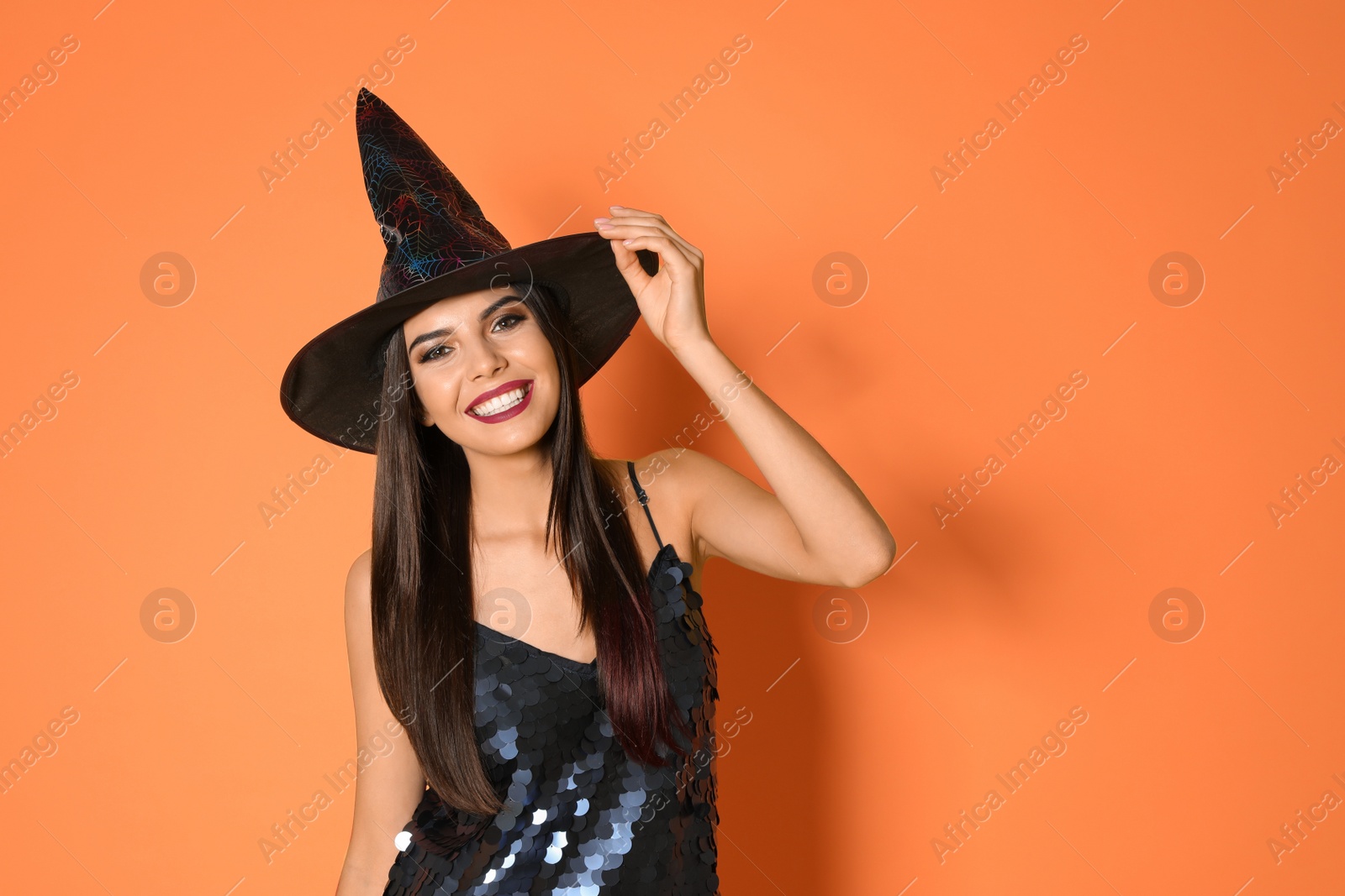 Photo of Beautiful woman wearing witch costume for Halloween party on yellow background, space for text