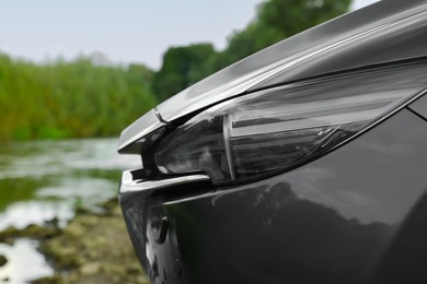 New black modern car outdoors, closeup of headlight