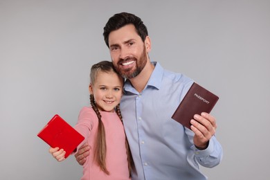 Immigration. Happy man and his daughter with passports on gray background