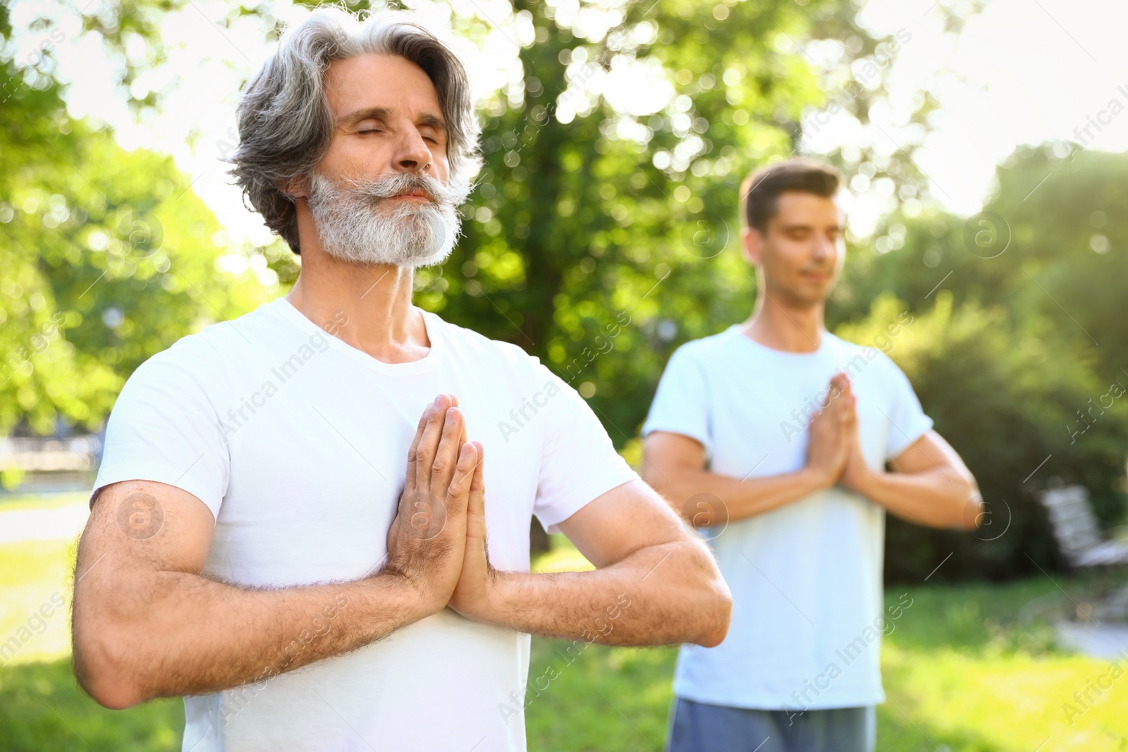 Photo of Men practicing morning yoga in sunny park