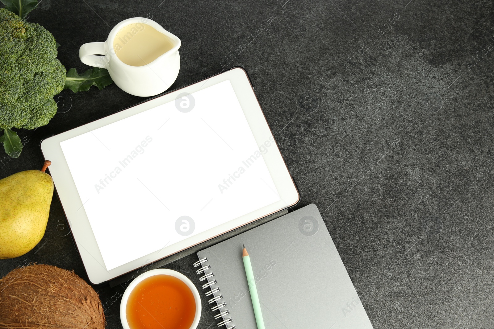 Photo of Glycemic index. Tablet with blank screen, different products and notebook on grey table, flat lay. Space for text