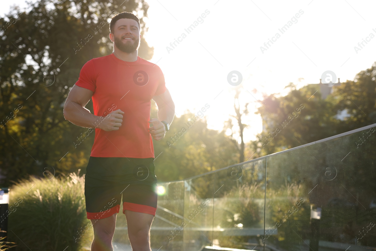 Photo of Happy man running outdoors on sunny day. Space for text