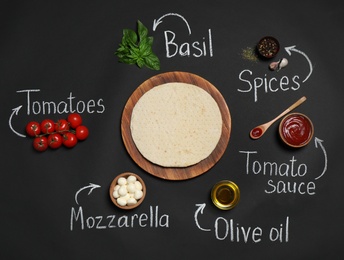 Pizza crust, ingredients and chalk written product's names on black background, flat lay
