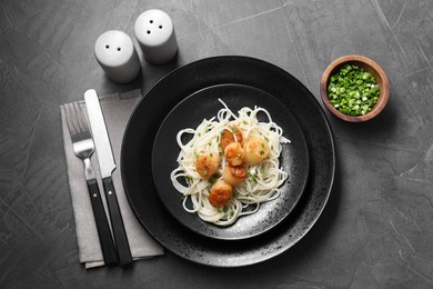 Photo of Delicious scallop pasta with green onion served on grey table, flat lay