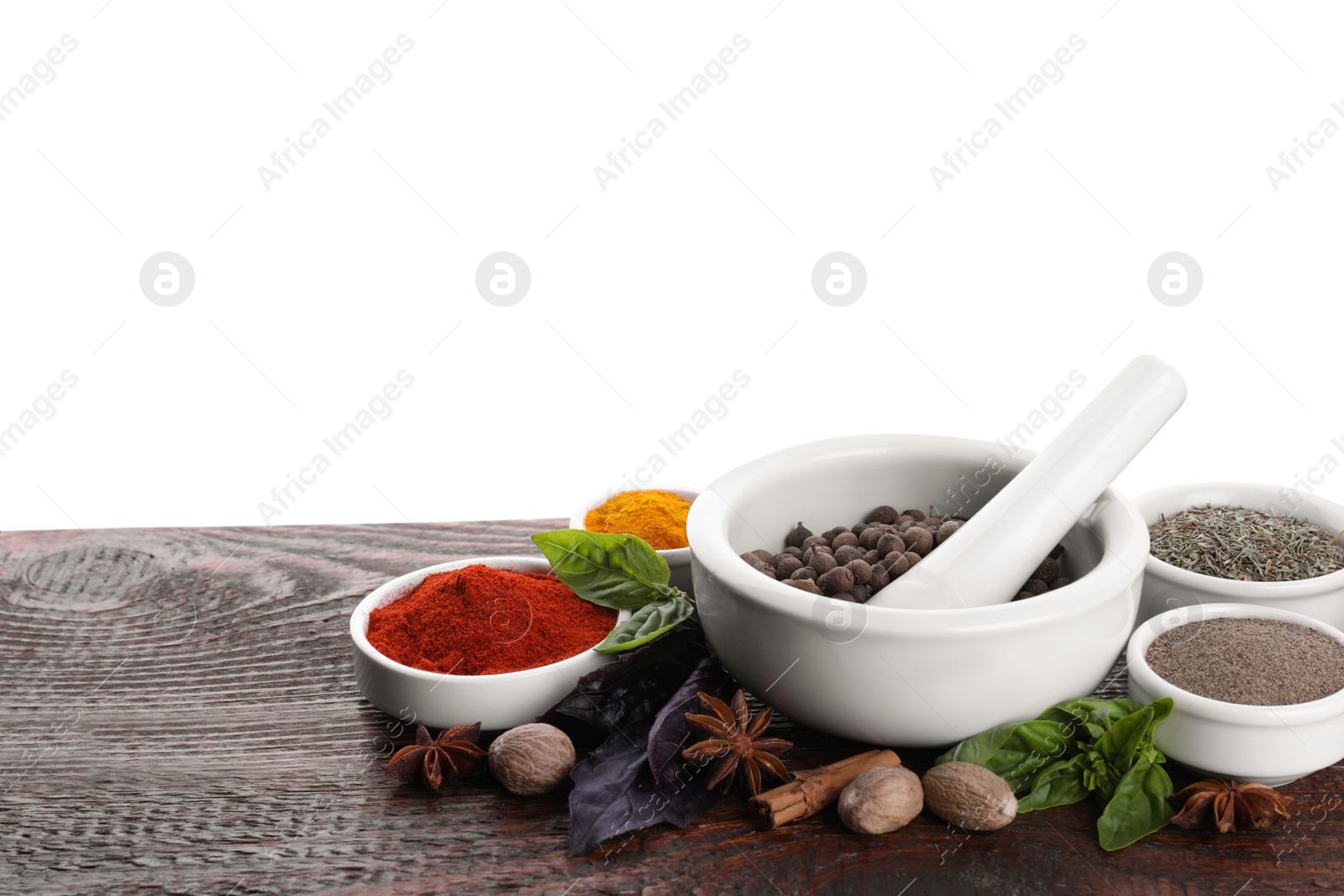 Photo of Mortar and different spices on wooden table against white background. Space for text