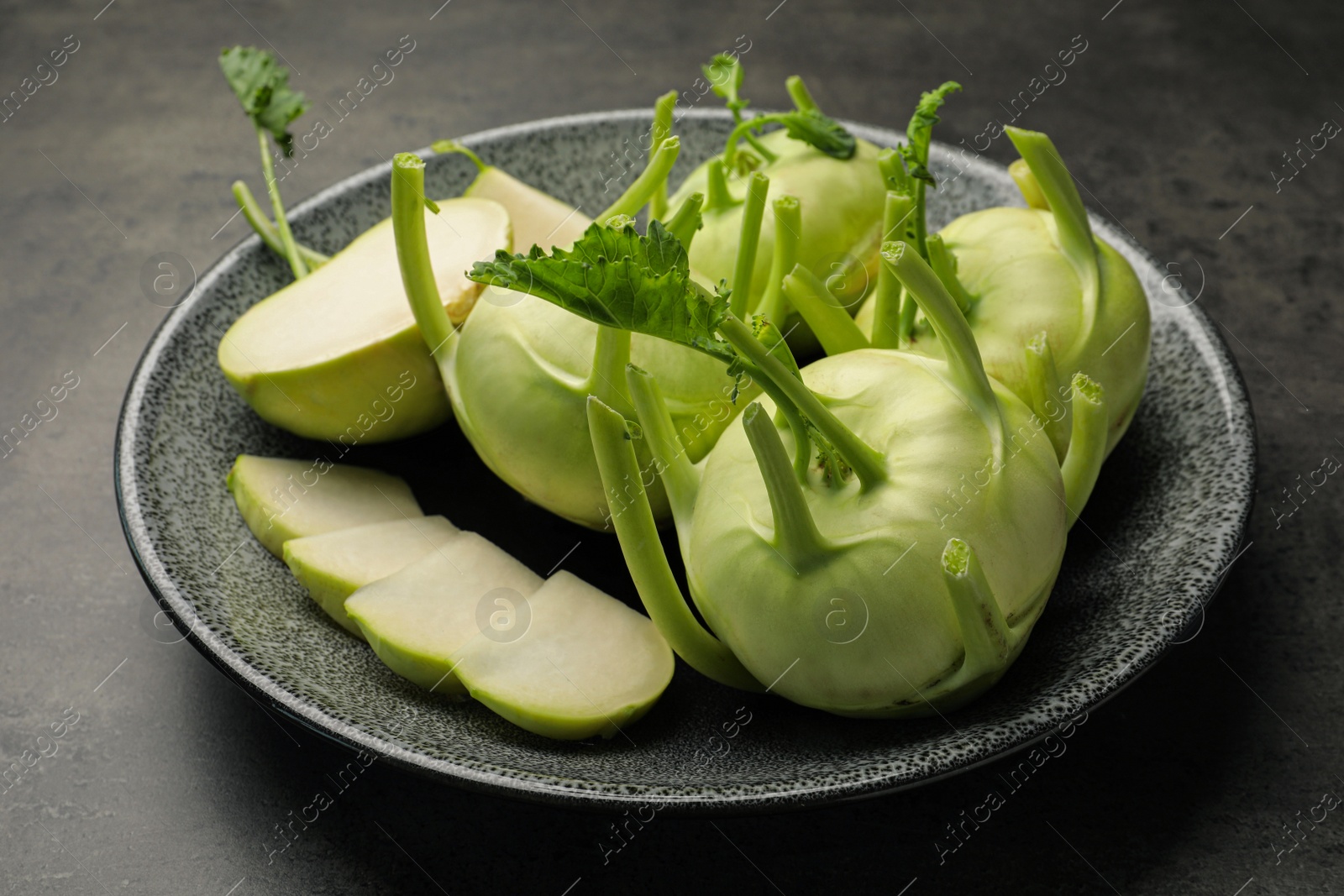 Photo of Whole and cut kohlrabi plants on grey table