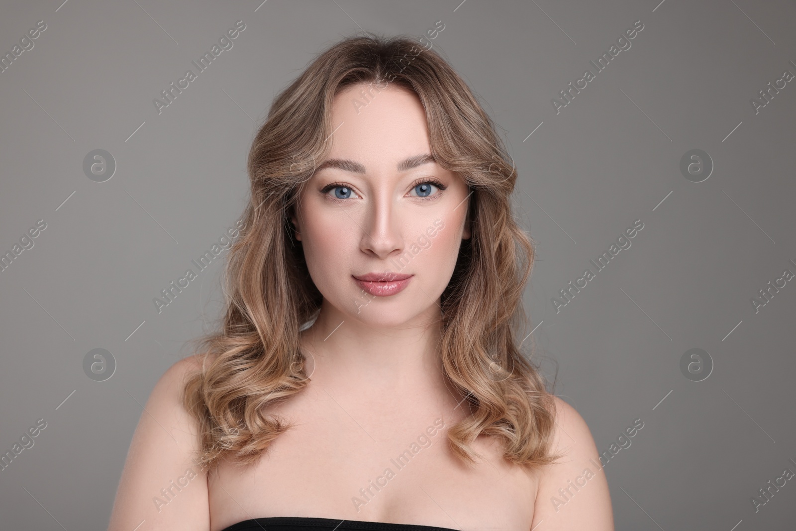 Photo of Portrait of beautiful woman with curly hair on grey background