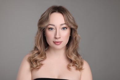 Portrait of beautiful woman with curly hair on grey background