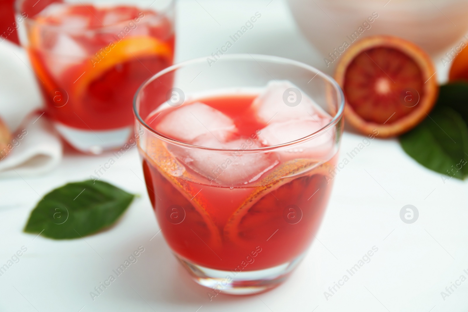 Photo of Tasty sicilian orange juice with ice cubes on white table, closeup