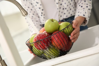 Woman washing fresh apples in kitchen sink, closeup