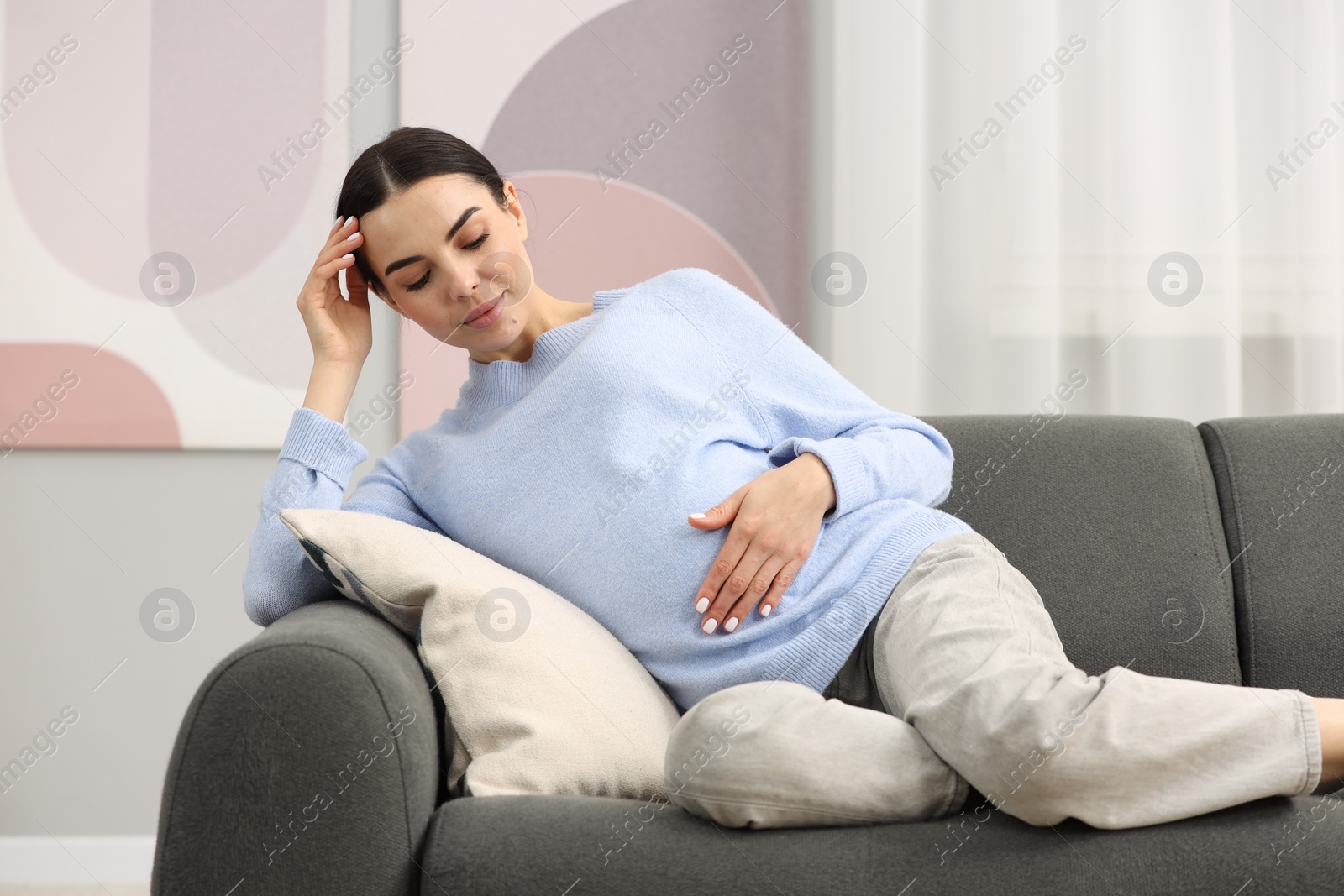 Photo of Pregnant young woman on sofa at home