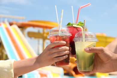 Photo of People with refreshing drinks in water park, closeup