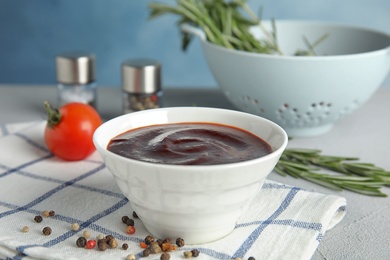 Photo of Bowl with tasty barbecue sauce on table