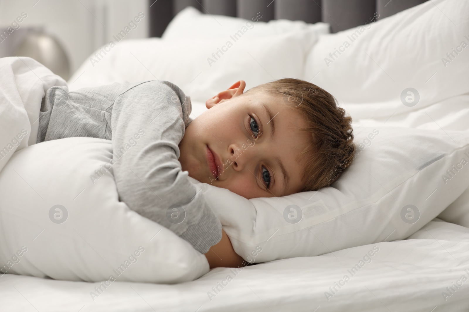 Photo of Sad little boy in bed at home