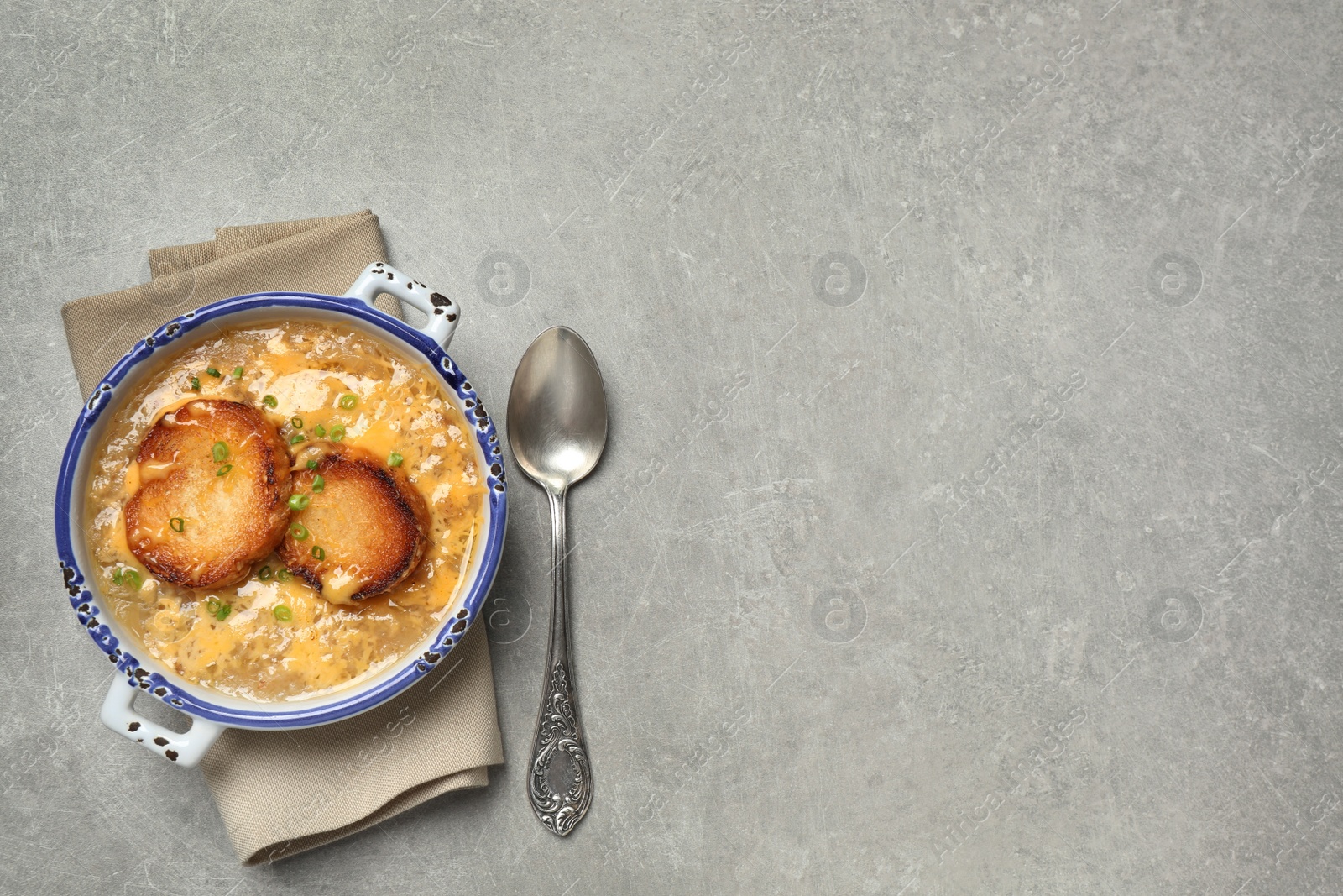 Photo of Tasty homemade french onion soup served on grey table, flat lay. Space for text