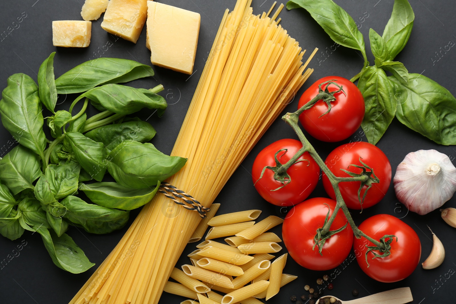 Photo of Different types of pasta, spices and products on black background, flat lay