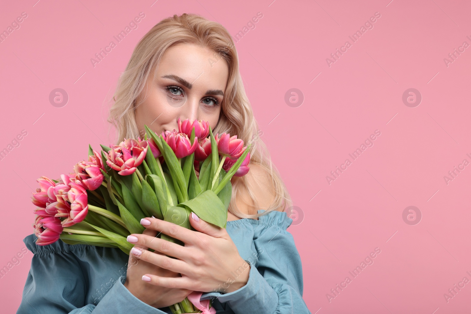 Photo of Happy young woman with beautiful bouquet on dusty pink background. Space for text