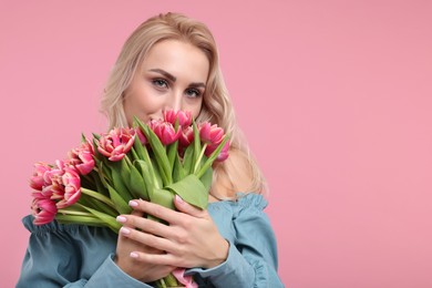 Happy young woman with beautiful bouquet on dusty pink background. Space for text