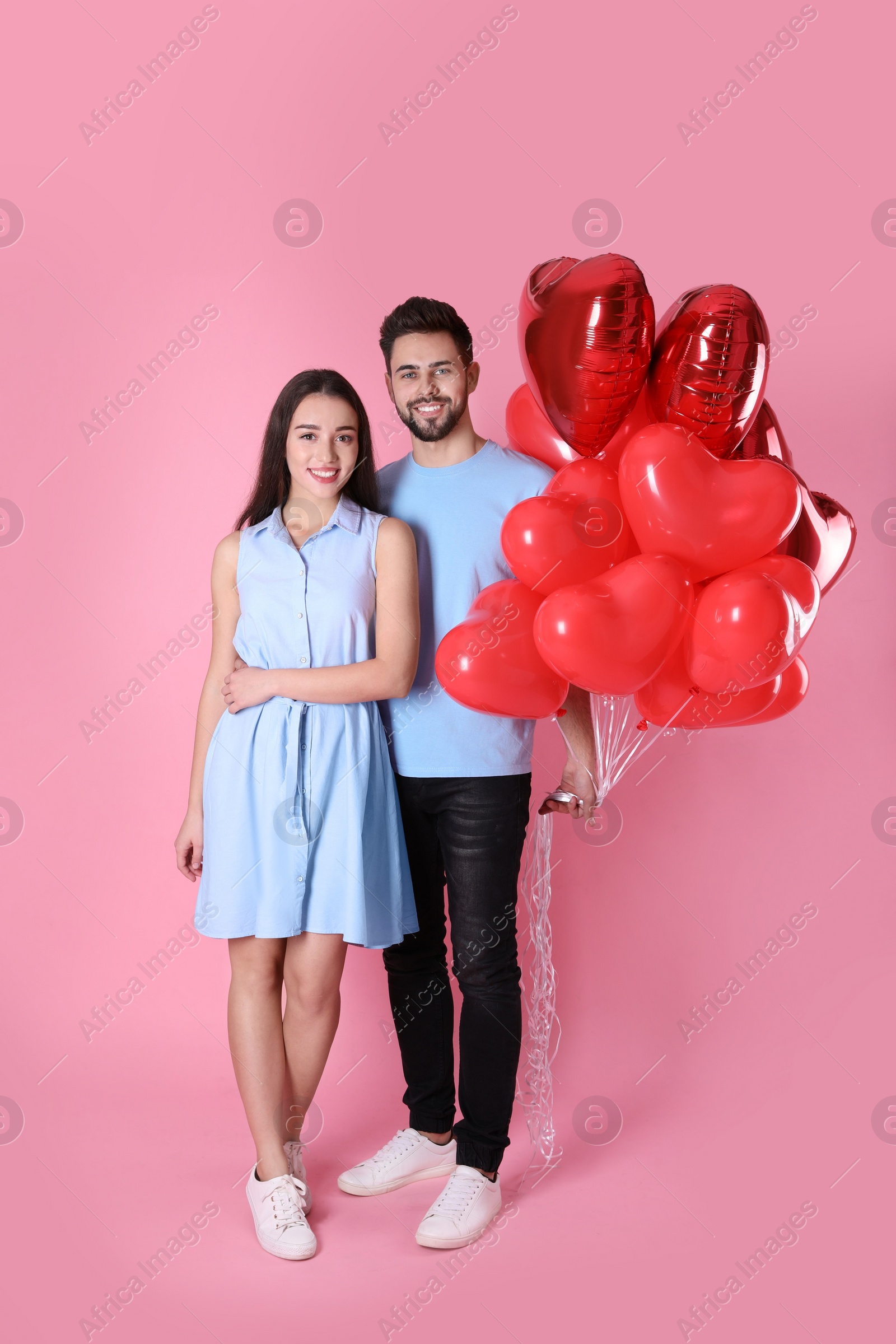 Photo of Lovely couple with heart shaped balloons on pink background. Valentine's day celebration