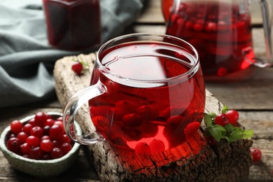 Photo of Delicious cranberry tea and berries on wooden table, closeup