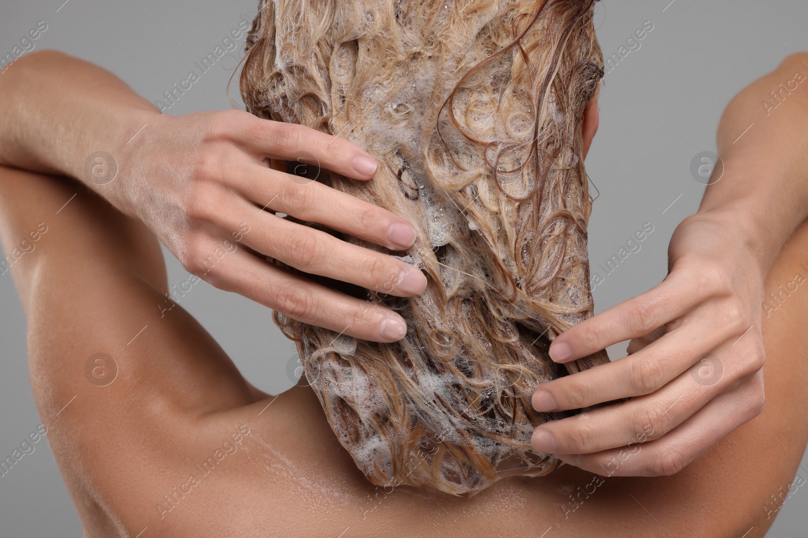 Photo of Woman washing hair on light grey background, back view