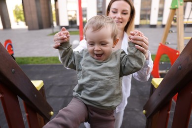 Photo of Happy nanny with cute little boy at playground