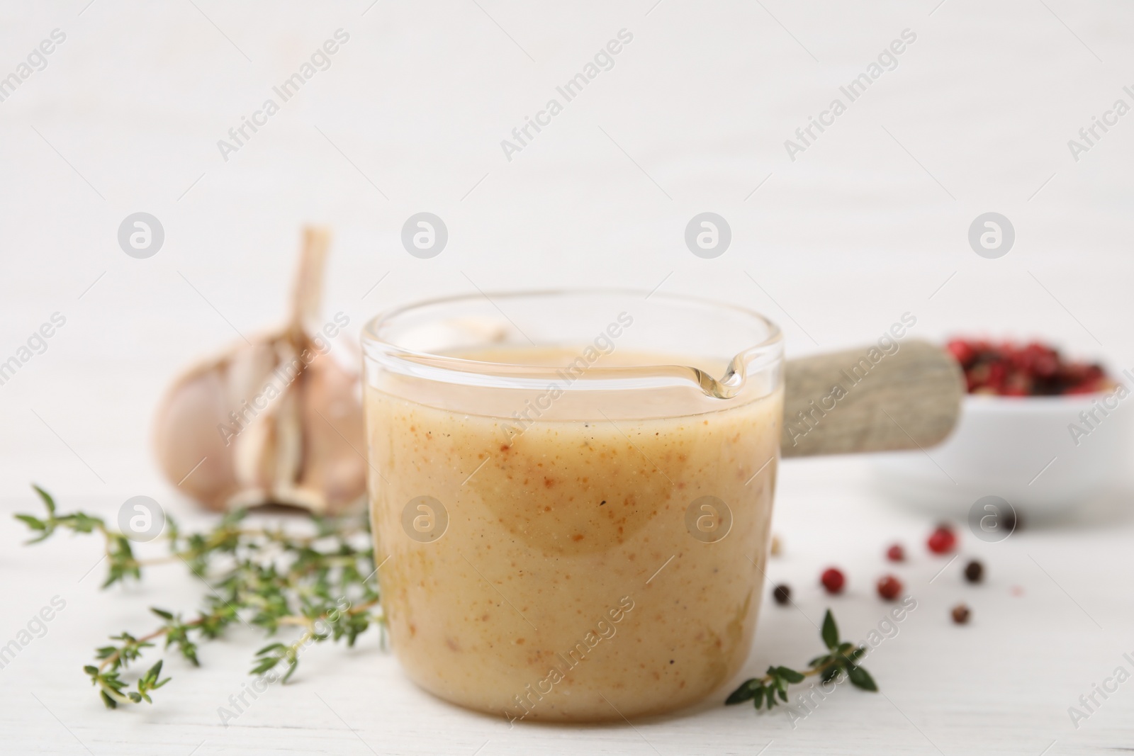 Photo of Delicious turkey gravy and thyme on white table, closeup