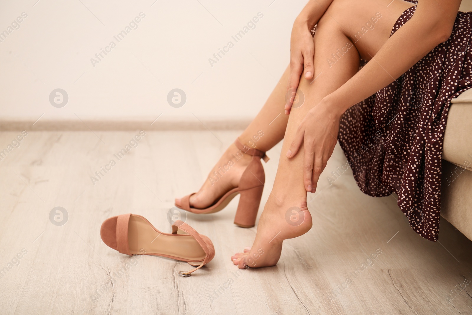 Photo of Woman taking off shoes at home, closeup. Tired feet after wearing high heels