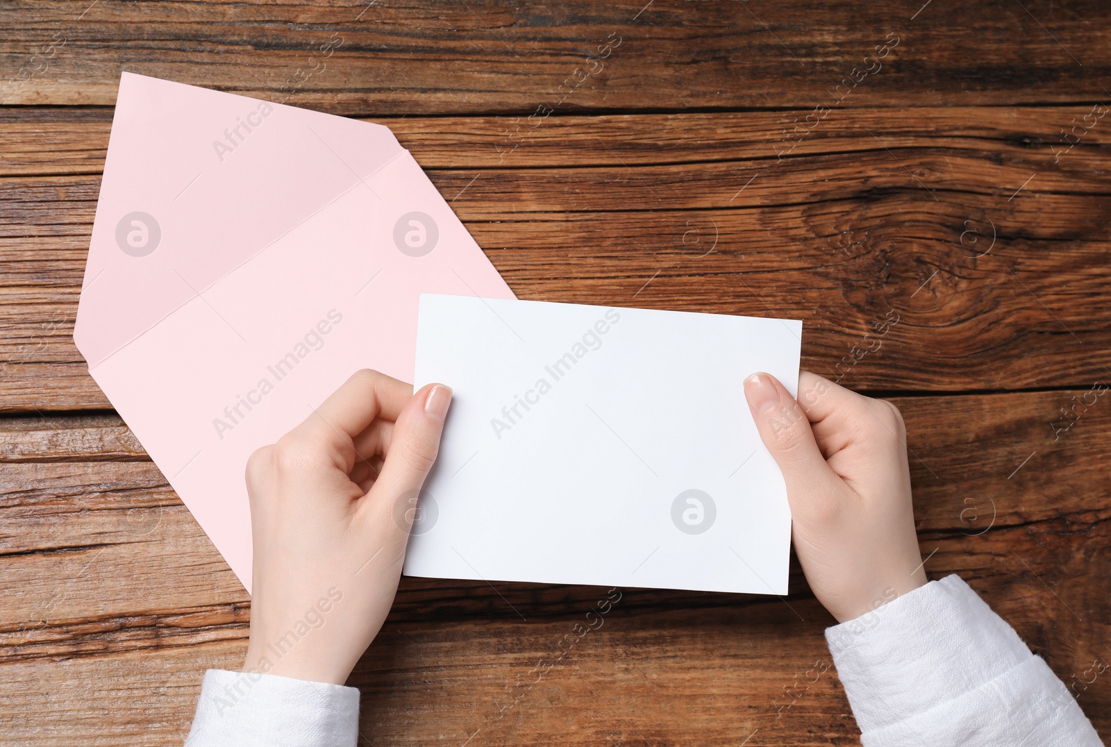 Photo of Woman with blank card at wooden table, top view. Space for text