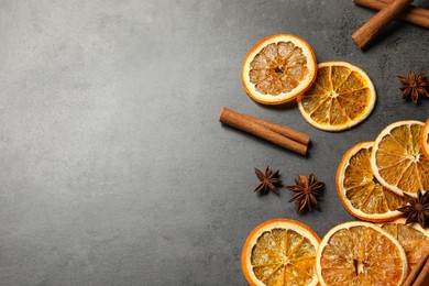 Photo of Dry orange slices, cinnamon sticks and anise stars on black table, space for text