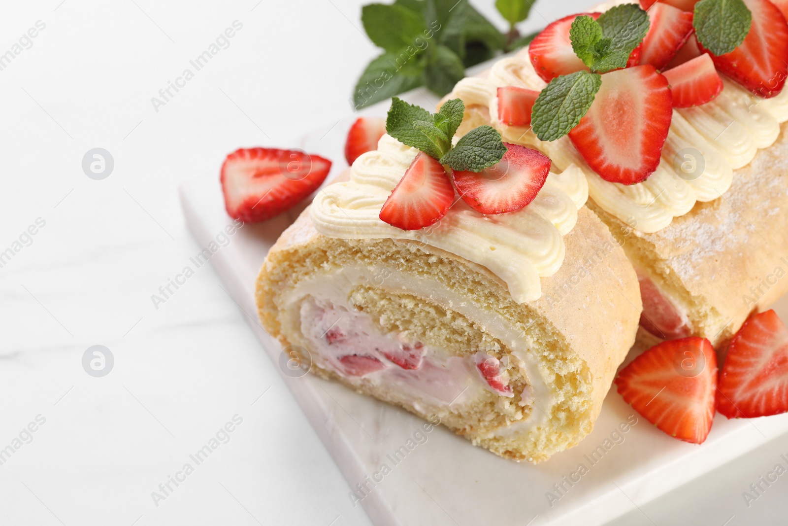 Photo of Delicious cake roll with strawberries and cream on white table, closeup. Space for text