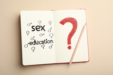 Image of Notebook with text Sex Education, question mark, female and male gender signs on beige background, top view