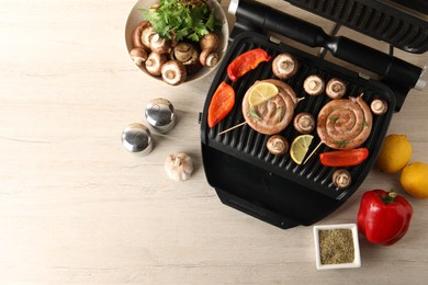 Photo of Flat lay composition with electric grill and homemade sausages on wooden table. Space for text