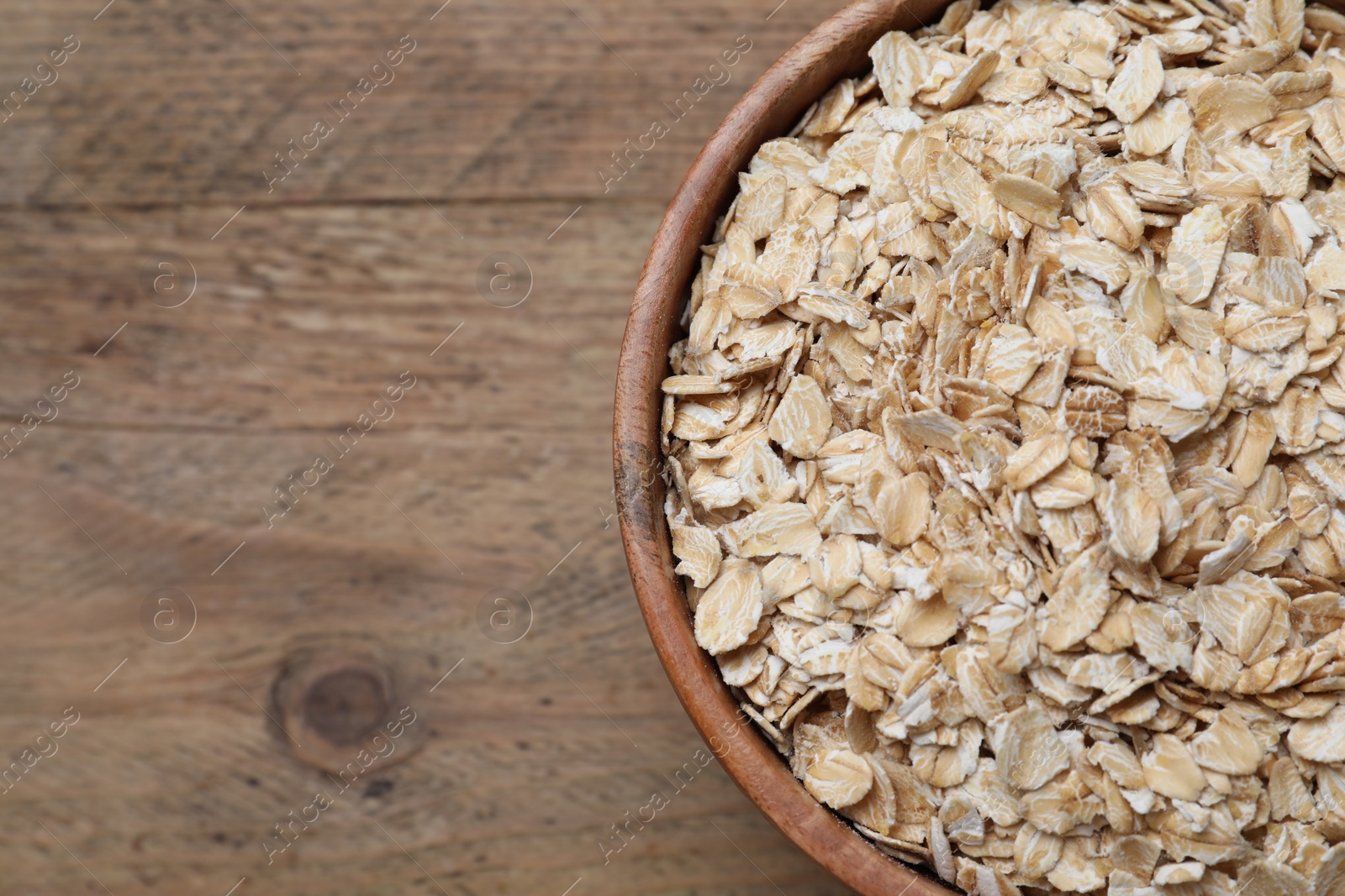 Photo of Bowl of oatmeal on wooden table, top view. Space for text
