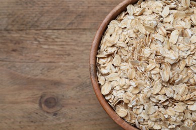 Bowl of oatmeal on wooden table, top view. Space for text