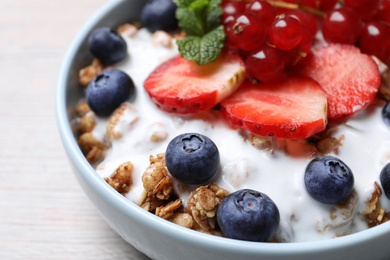 Photo of Delicious granola with fruits on wooden table, closeup