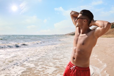 Photo of Handsome man with attractive body on beach. Space for text